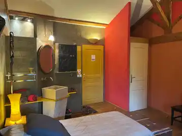 Chambre africaine - Entrée de la chambre avec porte des toilettes à droite et vasque simple avec serviettes disposées à gauche