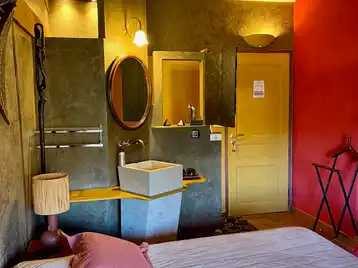 Chambre africaine - Entrée de la chambre avec vasque simple et luminaires allumés au-dessus du miroir