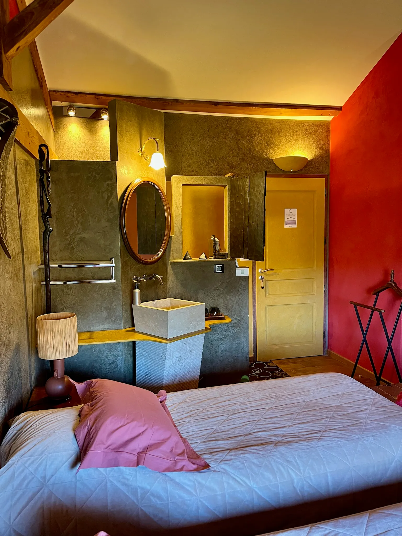 Chambre africaine - Entrée de la chambre avec vasque simple et luminaires allumés au-dessus du miroir