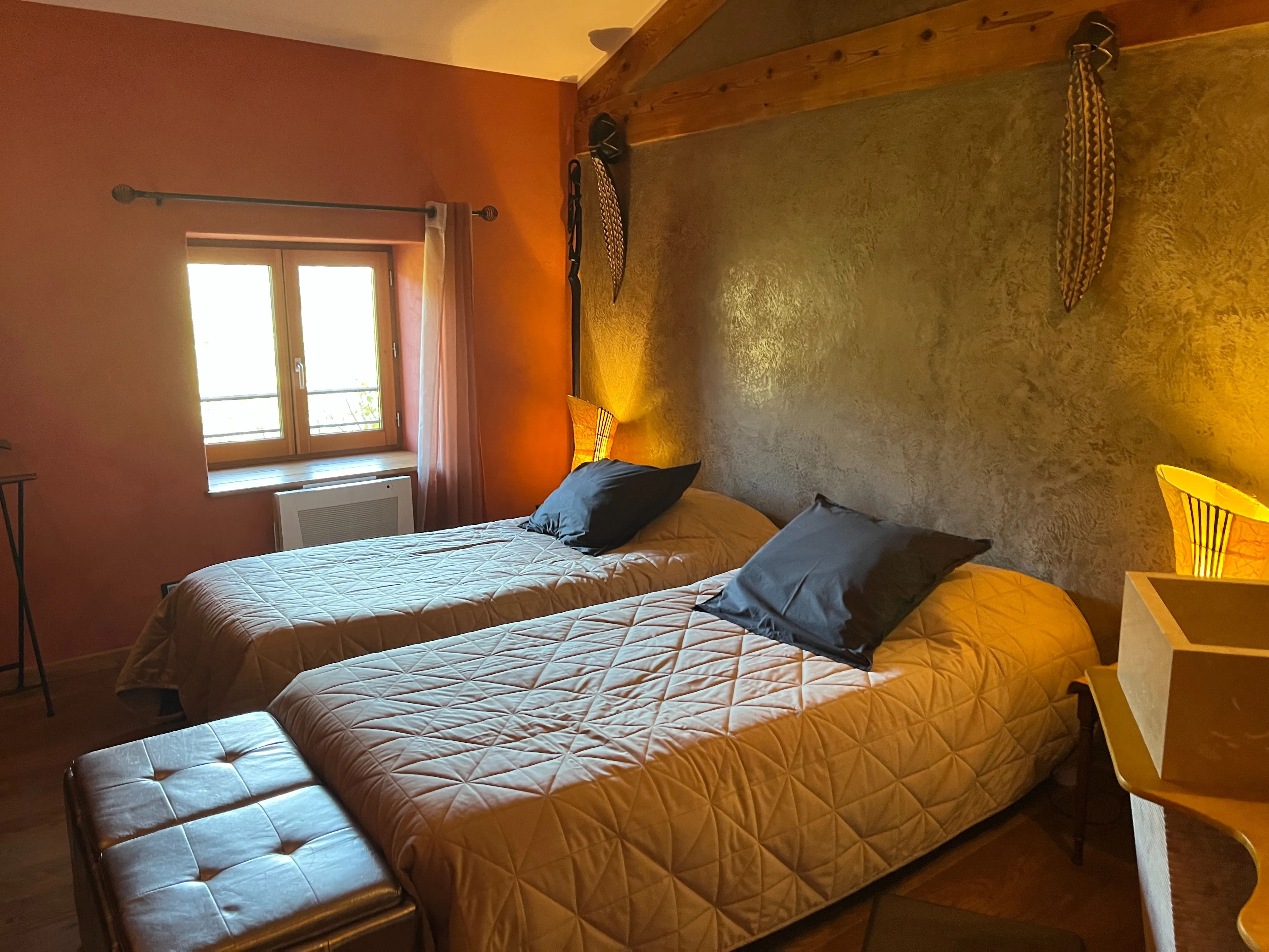 Chambre africaine - Lits jumeaux avec lampe de chevet allumée et fenêtre ouverte sur le jardin
