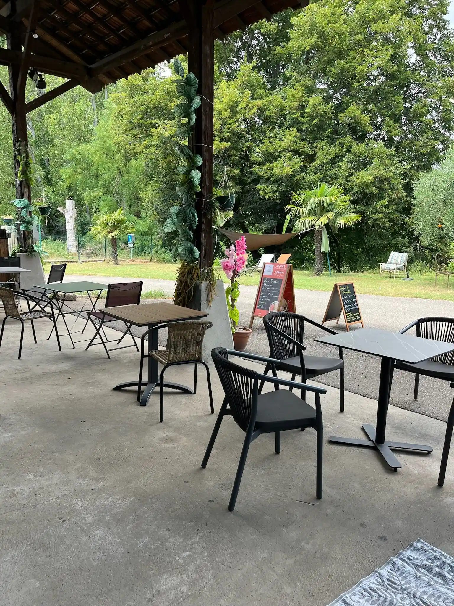 Terrasse du Comptoir de Pipangaille à l’entrée du domaine avec tables installées et transats dans l’herbe