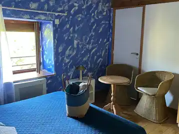 Chambre créole - Coin bureau de la chambre avec serviettes disposées sur le lit et vue sur le jardin par la fenêtre