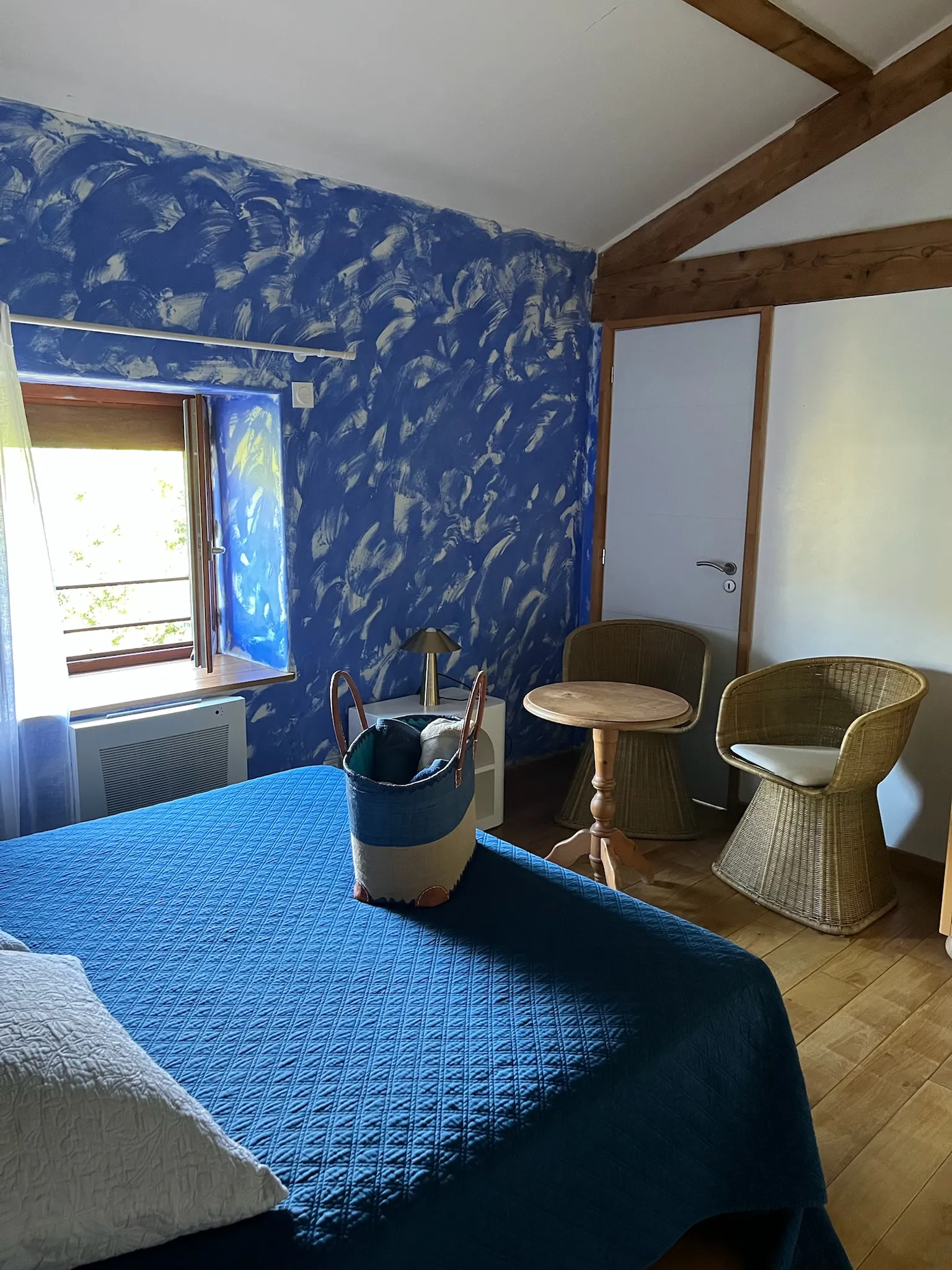 Chambre créole - Coin bureau de la chambre avec serviettes disposées sur le lit et vue sur le jardin par la fenêtre