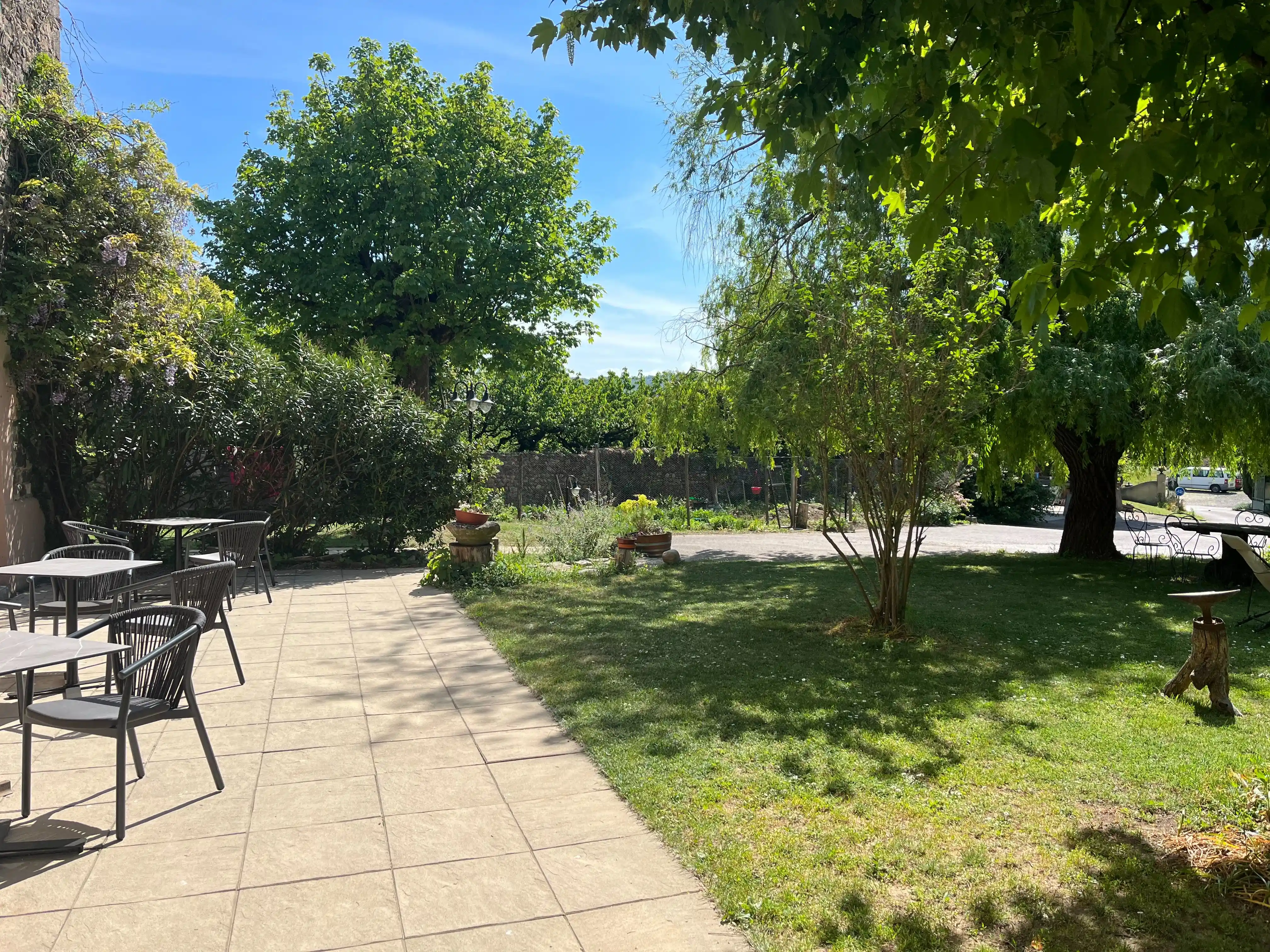 Terrasse du domaine côté jardin avec vue sur les grands arbres baignée de soleil