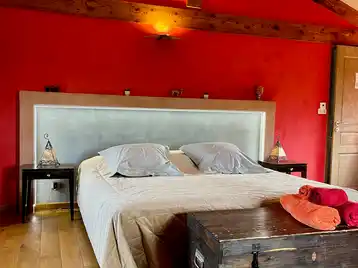 Suite marocaine - Lit double vu de face avec tête de lit éclairée et serviettes disposées sur le coffre au pied du lit