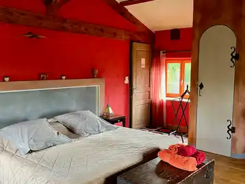 Suite marocaine - Lit double vu de côté avec porte de la chambre, fenêtre sur cour et serviettes disposées sur le coffre au pied du lit