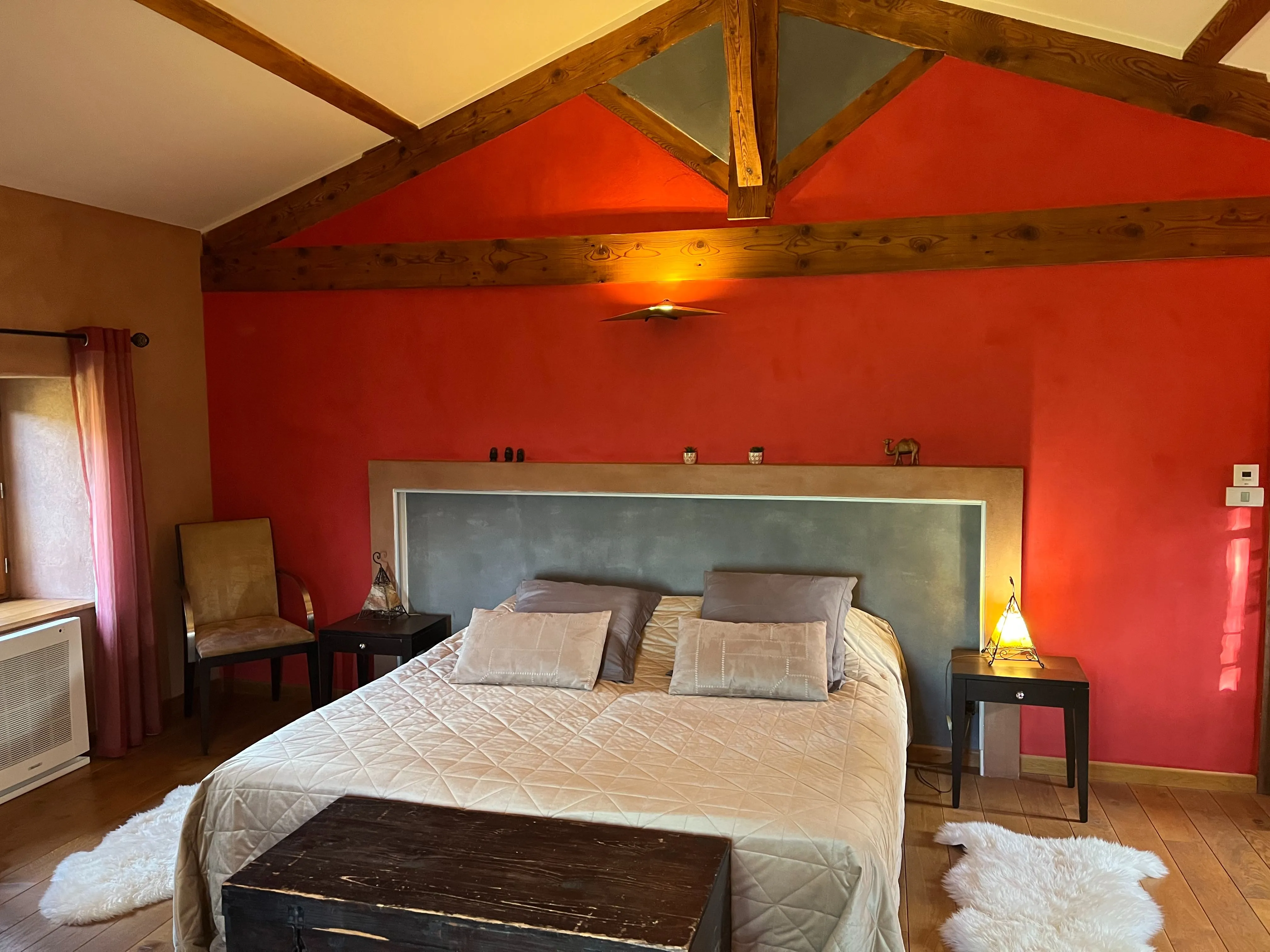 Suite marocaine - Lit double avec lampes de chevet allumées, mur rouge et charpente en bois apparente