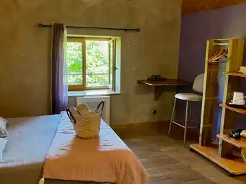 Chambre toscane - Chambre baignée de lumière avec vue sur le jardin, serviettes disposées sur le lit et espace de rangement pour les vêtements